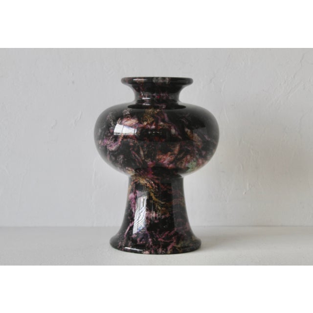 Fabulous vase made of a dark stone with purple, pink, and white veins, featuring a pedestal base and a wide, rounded body....