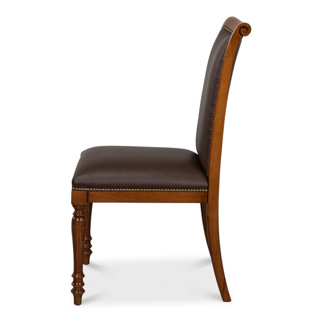 Rows of nailheads follow the outline of the brown upholstery, catching light along every leather edge. That trim, over a...