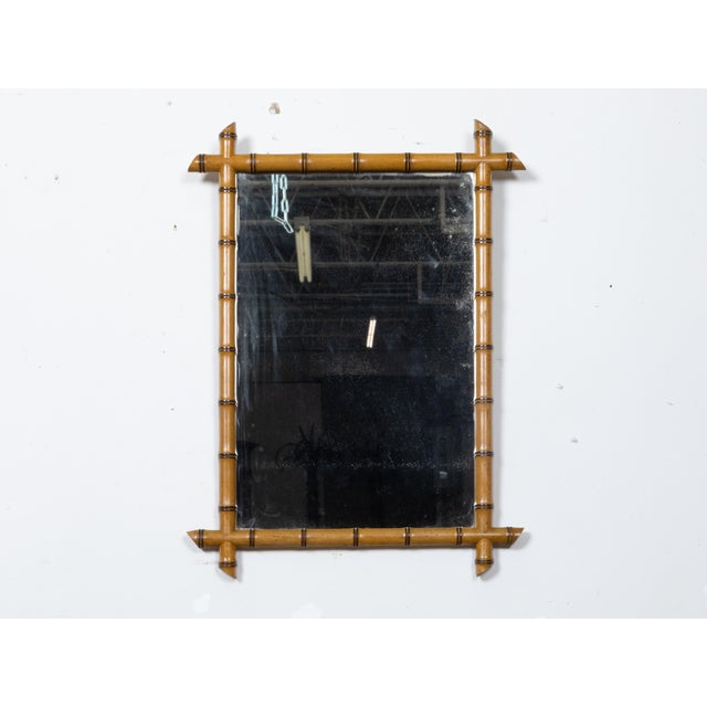 A French Turn of the Century walnut faux bamboo mirror from circa 1900 with light brown color and intersecting corners....