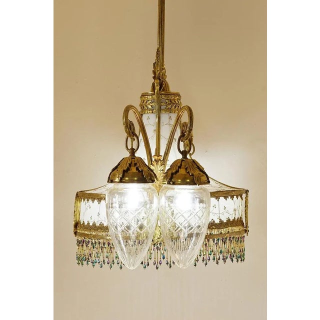 Art nouveau chandelier (liberty), made of golden brass, decorated with floral motifs, leaves and geometric figures. In the...