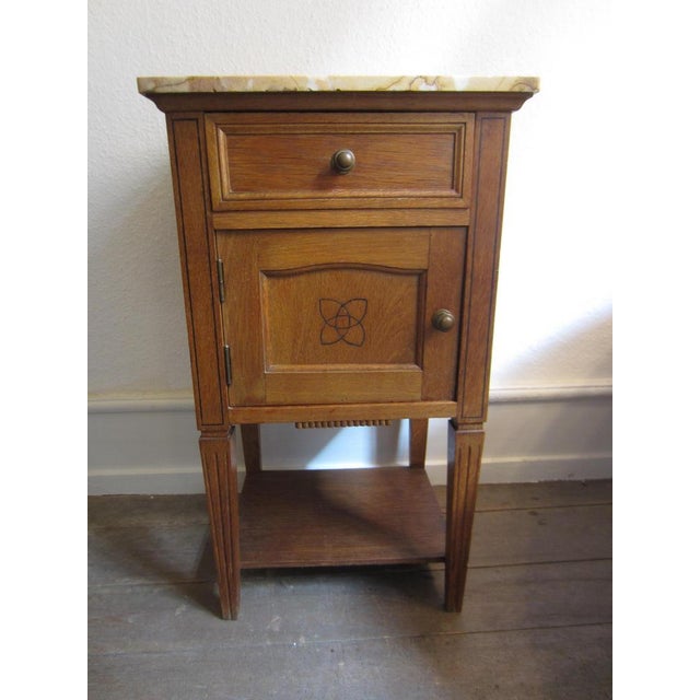 Charming bedside table made of solid wood with a light apricot-beige marble top, circa 1900, in a simple French country,...