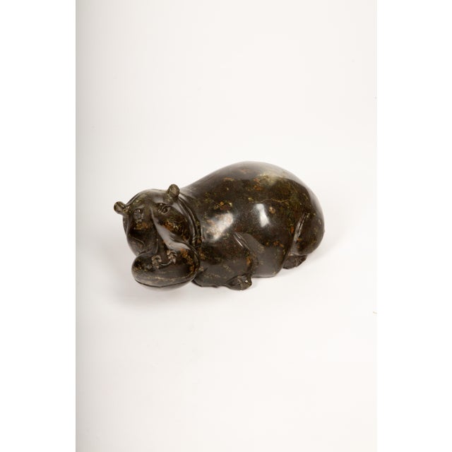 This charming 12-inch hippopotamus sculpture is hand-carved from richly veined, dark green soapstone native to Zimbabwe,...