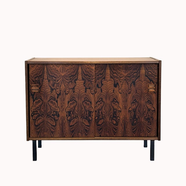A stunning small vintage cabinet crafted in Brazilian rosewood with sliding doors and a stunning grain detail enhancing...