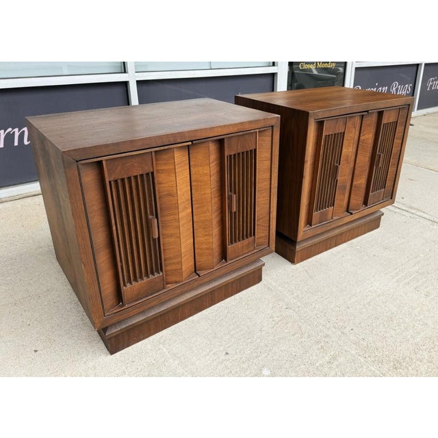 This pair of 1970s Brutalist-inspired nightstands, made in Canada, features bold geometric door fronts, warm wood tones,...