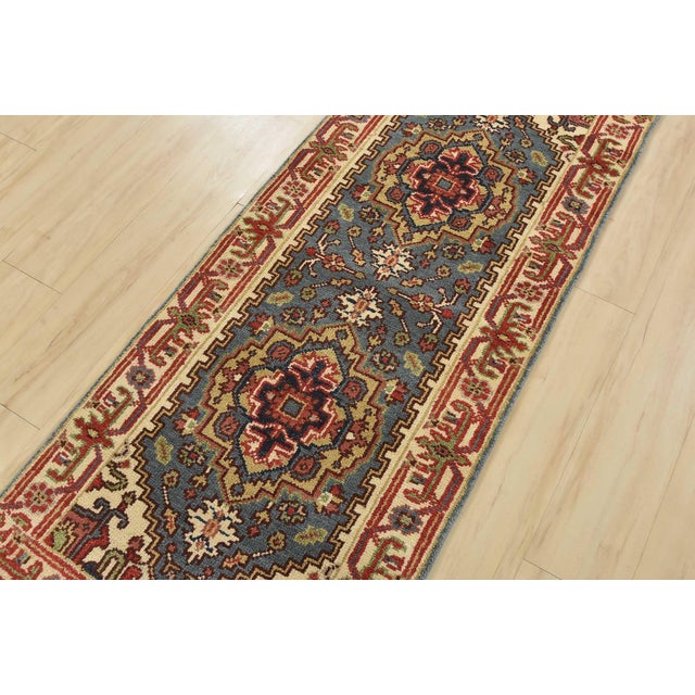 A traditional tribal Heriz runner hand-knotted with an all-wool pile on a cotton foundation. This oriental rug features...