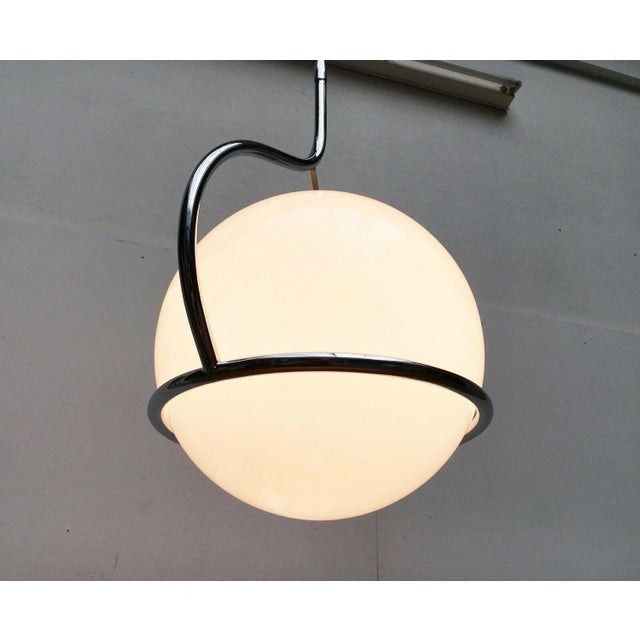 Elegant space age pendant lamp of italian origin. an impressive yet simple design. A large glass ball is held in an...