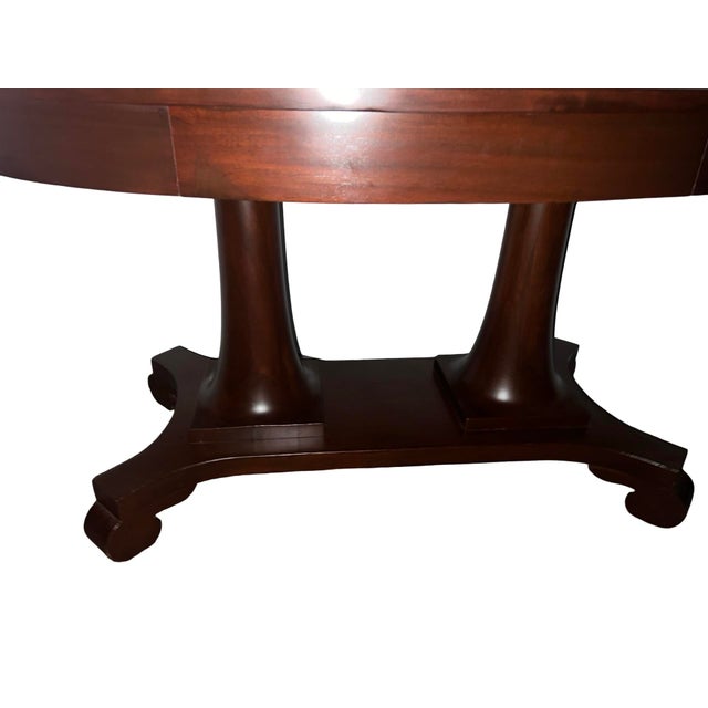 Elegant American Empire style mahogany center table or desk dating to the early 1900s, featuring a large oval top with...