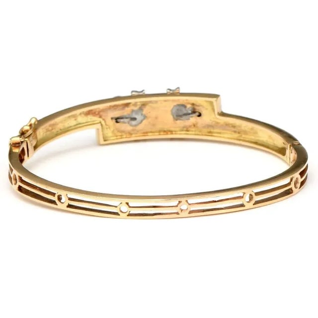 This enchanting vintage bangle bracelet of 14K yellow gold boasts an edgy cross-over jet-black enameled band top. A single...