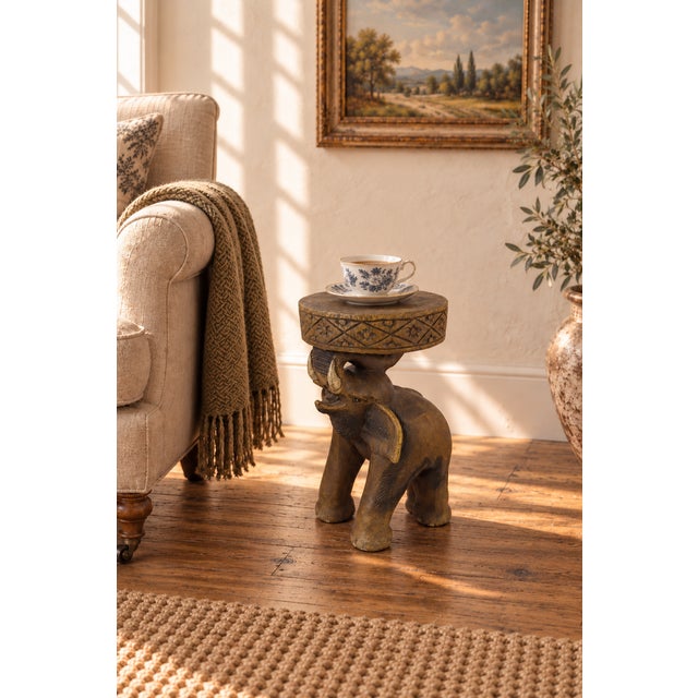 A sculptural vintage elephant side table or stool, hand-carved from a single solid block of tropical hardwood and likely...
