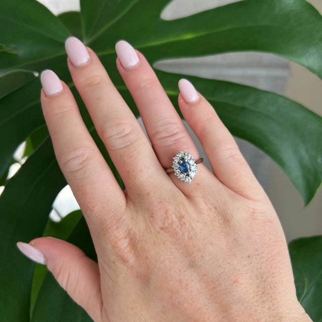Vintage ring in 18 carat white gold (750 thousandths). It is decorated with diamonds surrounding a natural oval sapphire....