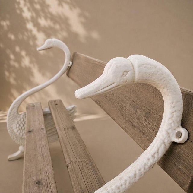 An elegant 20th-century French garden bench featuring a cast-metal frame and a wooden seat. The piece is distinguished by...