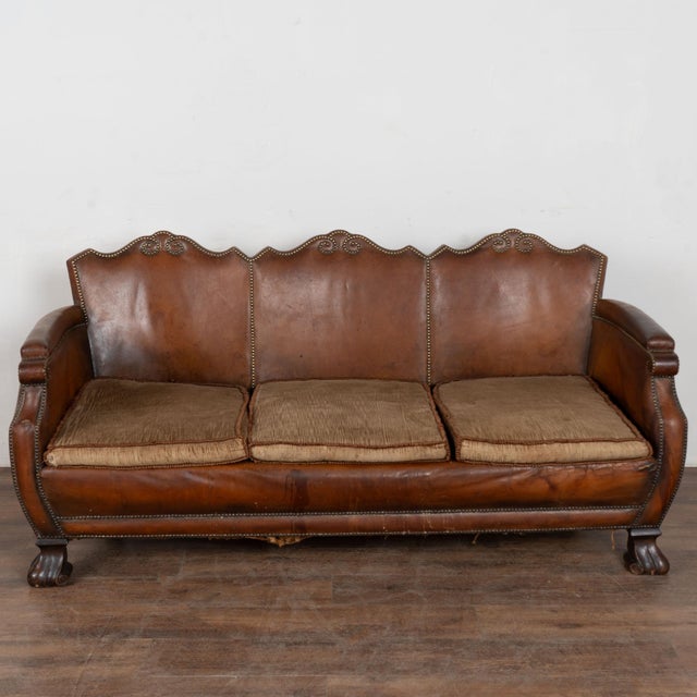 20th century vintage Danish three-seat sofa upholstered in brown leather. Decorative nail head trim and the camelback...