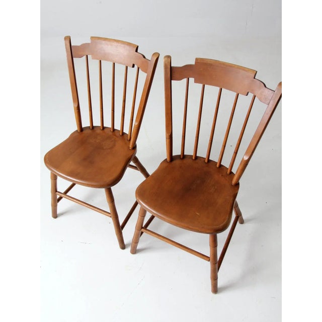 A pair of mid-20th-century dining chairs by Conant Ball, featuring a modern interpretation of the classic Windsor side...