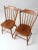 A pair of mid-20th-century dining chairs by Conant Ball, featuring a modern interpretation of the classic Windsor side...
