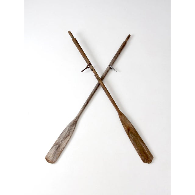 Pair of vintage wooden boat oars featuring weathered wood, long tapered blades, and beautifully aged finishes that...