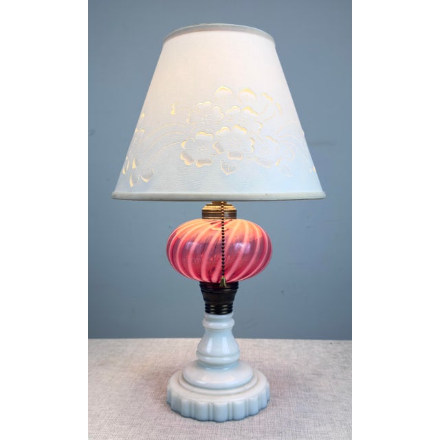 A beautiful old converted oil lamp with swirled cranberry glass body, deco style milk glass base and cut and pierced...