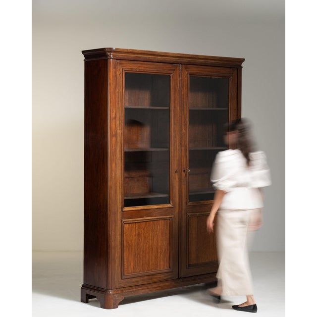 This piece presents as a bookcase, distinguished by dark mahogany, glass door, open shelving. It was made in France during...