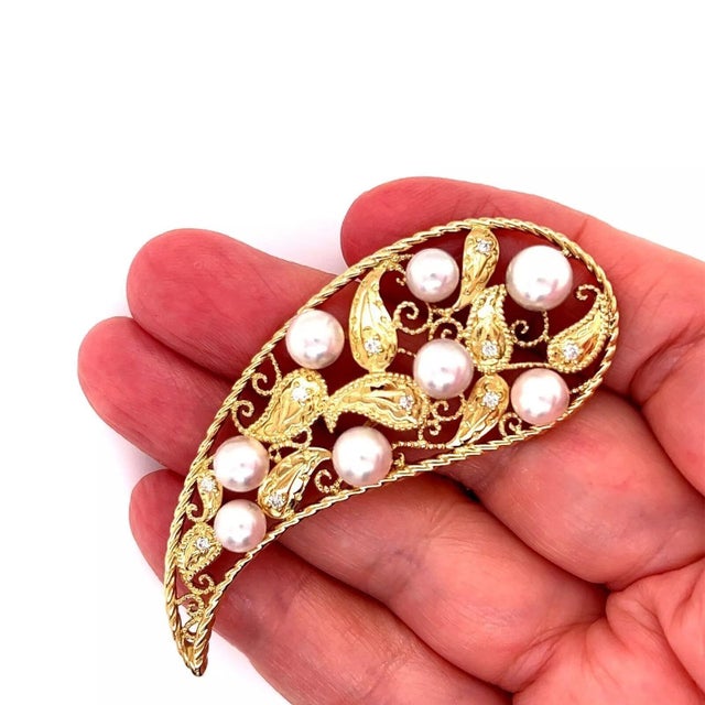This is a stunning long brooch by Mikimoto, crafted from 18k yellow gold featuring a long large open design teardrop shape...