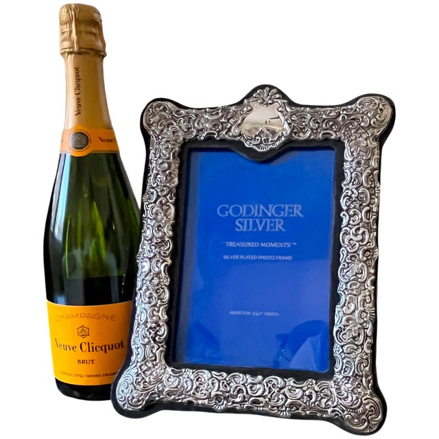 An elegant silverplated picture frame by Godinger from its “Treasured Moments” collection, featuring an elaborate border...