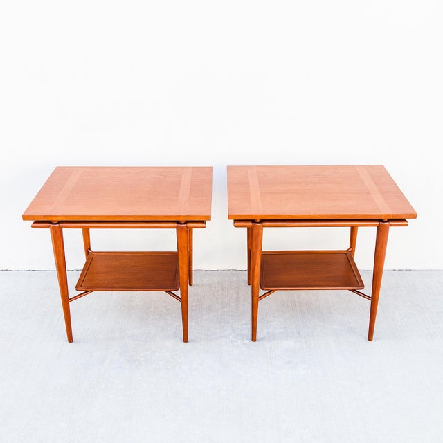 An expertly restored pair of two-tier floating top side or end tables, produced by Widdicomb c. 1950s with design...