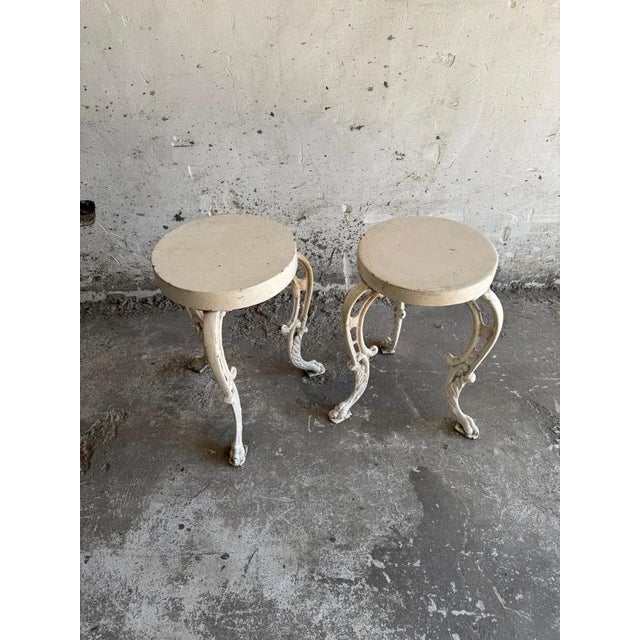 Set of two antique cast iron side tables These elegant tables combine a round wooden top with gracefully shaped cast iron...