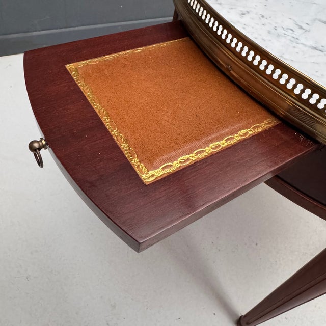 Charming round French Louis XVI style bouillotte side table crafted in rich mahogany. It features a white marble top...