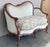 An antique Victorian sofa offers walnut frame in serpentine form having carved floral crest over button back upholstery,...