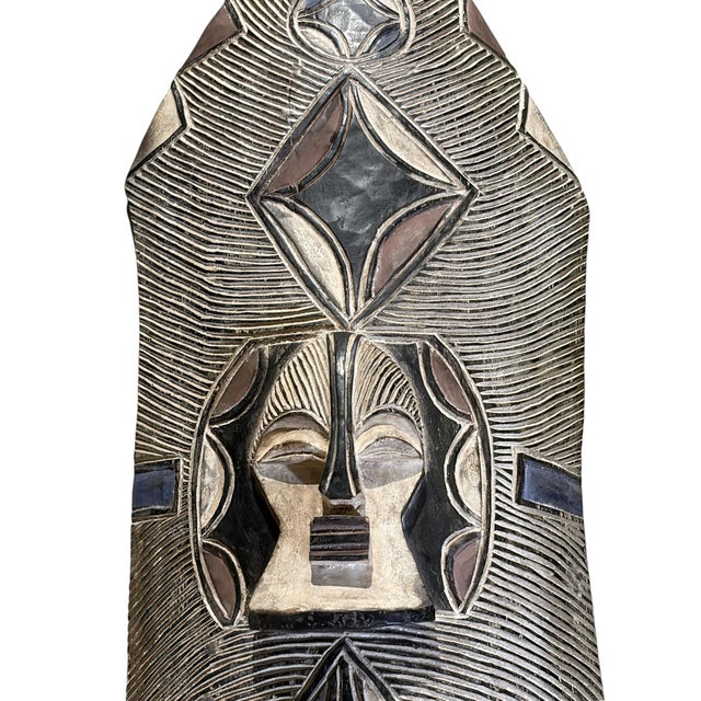 A hand-carved shield from the Bamileke people of Cameroon, meticulously carved from a single piece of wood. This striking...