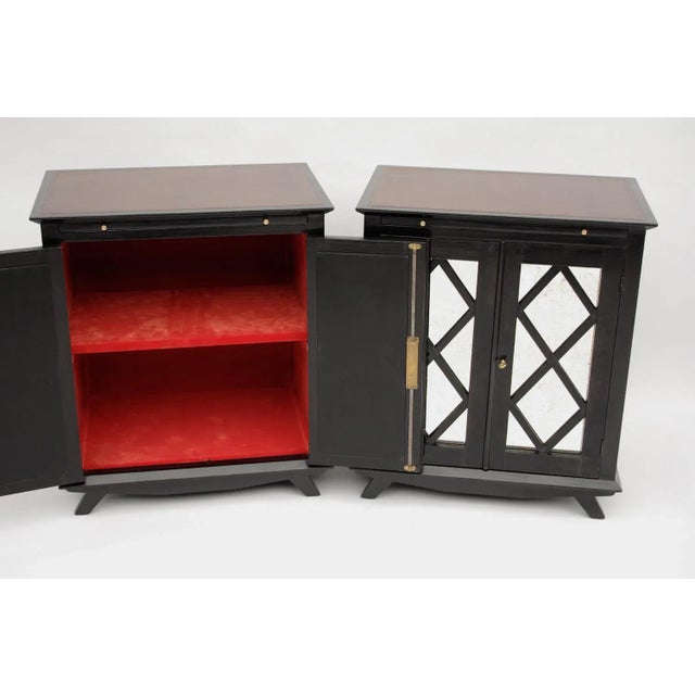 This pair of black lacquered rectangular cabinets standing on four little legs open with two panels decorated with braces...