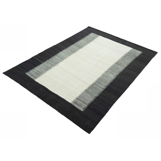 This modern Kilim rug impresses with its minimalist, graphic design with a strong contrast effect. The elegant combination...