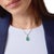 This elegant pendant necklace showcases a captivating pear-shaped cabochon emerald, glowing with rich green depth and a...