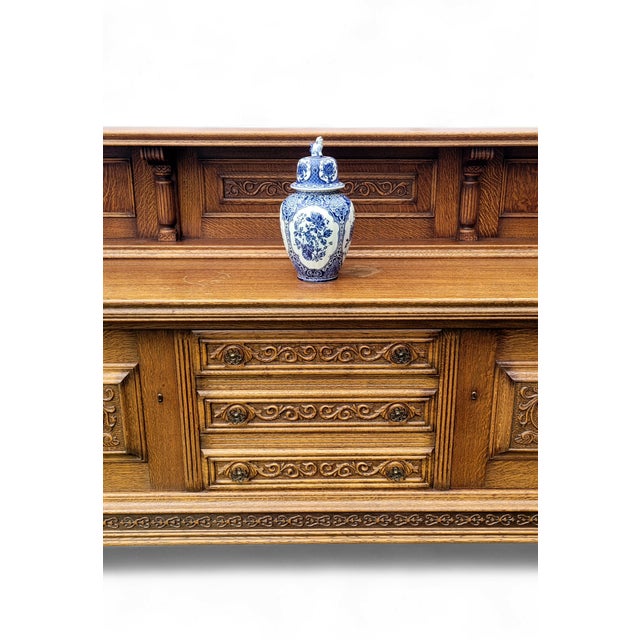 An imposing and beautifully preserved 20th-century carved oak buffet sideboard, distinguished by its architectural...