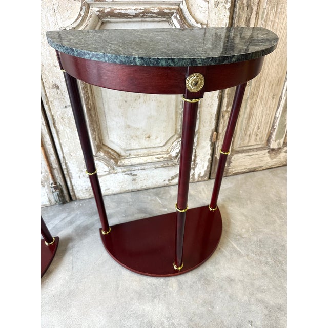 Pair of mahogany console tables/bedside tables with crescent-shaped green marble tops. The columns are adorned with rings....