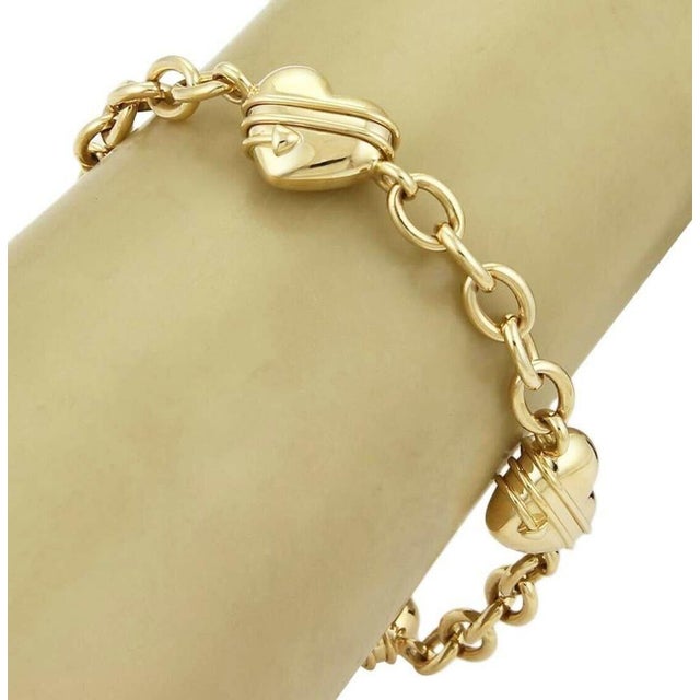 The Tiffany & Co. 18k Yellow Gold Cupid 4 Heart Charms Oval Chain Link Bracelet is a luxurious and elegant piece of fine...