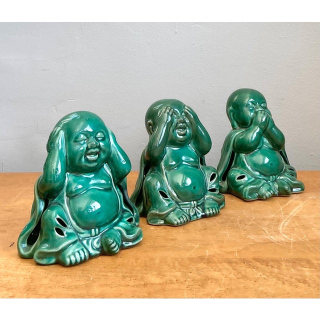 This charming set of three vintage ceramic Buddha figurines offers a playful yet serene interpretation of the classic "see...