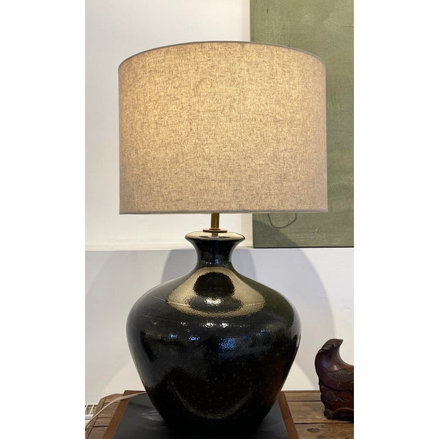 A striking 1960s ceramic table lamp featuring a richly textured lava glaze with organic, cratered patterning—an...