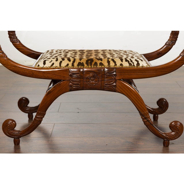 A pair of English Regency mahogany stools from the 19th century with large scrolling arms and legs, carved foliage and...