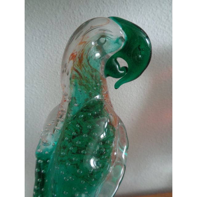 Vintage blown glass parrot with controlled bubbles throughout sculpture.. The bright green color is unusual. The bird sits...