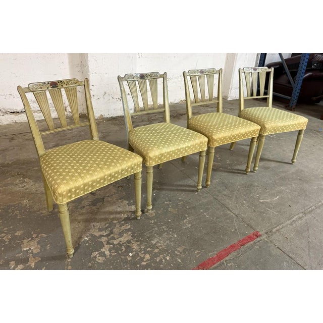 This set of four Neoclassical-style dining chairs features elegant arrow-back construction, tapered legs, and a softly...