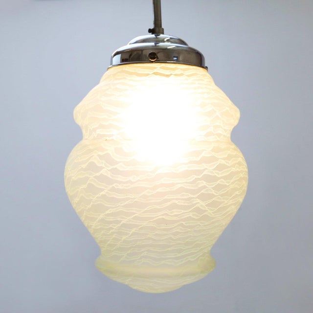 An elegant French Art Deco pendant lamp from the 1940s, featuring a sculptural frosted glass shade with a softly...