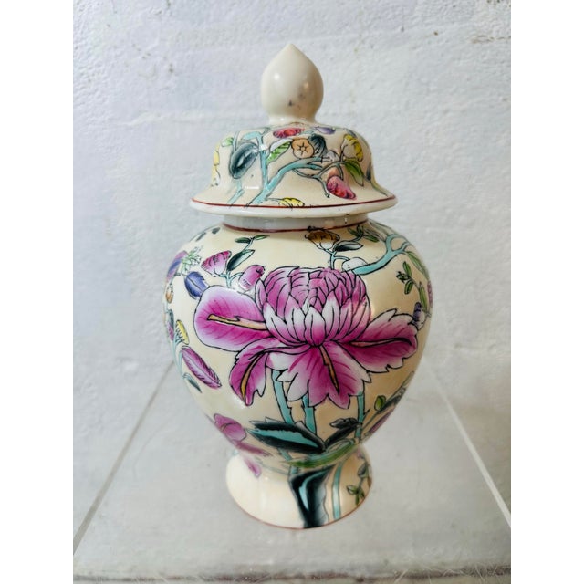 This is a decorative porcelain ginger jar with a lid, featuring a cream/white ground and hand-painted floral designs in...