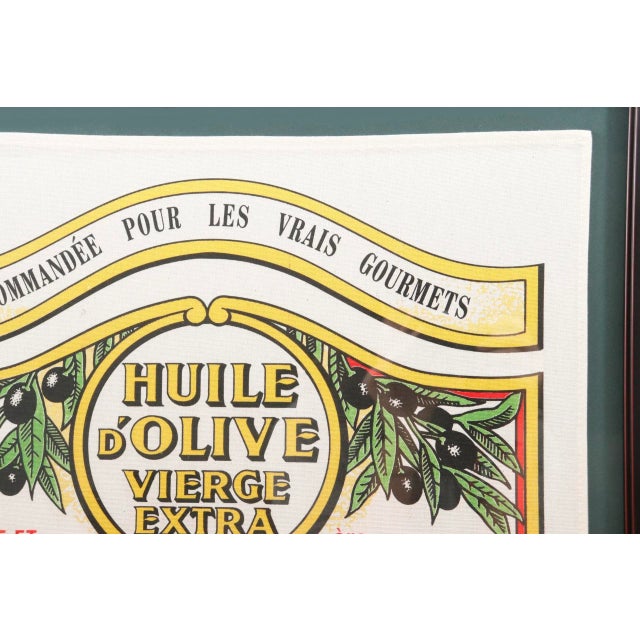 A framed French tea towel made of cotton, decorated with a vintage Nicolas Alziari Huile d'Olive label. Maison Alziari has...