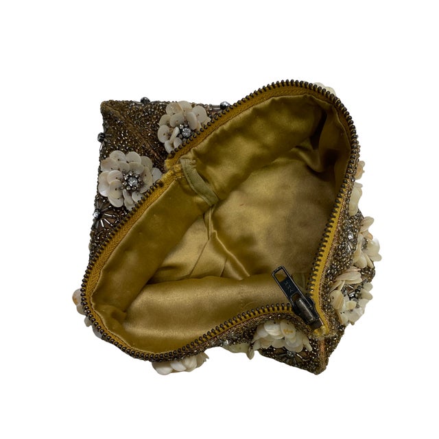 A richly embellished vintage evening clutch handcrafted in India, featuring dense metallic gold-tone beadwork accented...
