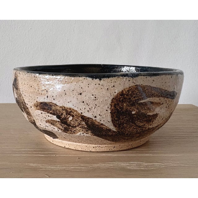 A distinctive American studio pottery bowl from New York, decorated with expressive dark brown brushwork over a warm...