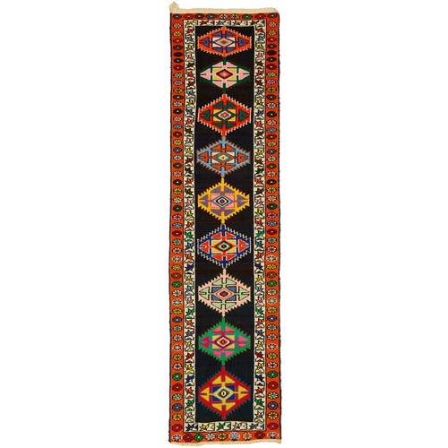 This exquisite runner rug is a rare example of tribal craftsmanship, hand-knotted by the women of the Herki tribe during...