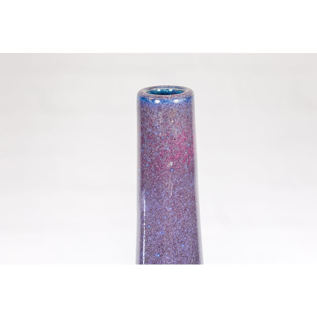 A multicolor purple, blue, pink and white ceramic vase with tapering lines. This vibrant ceramic vase, with its eye-...