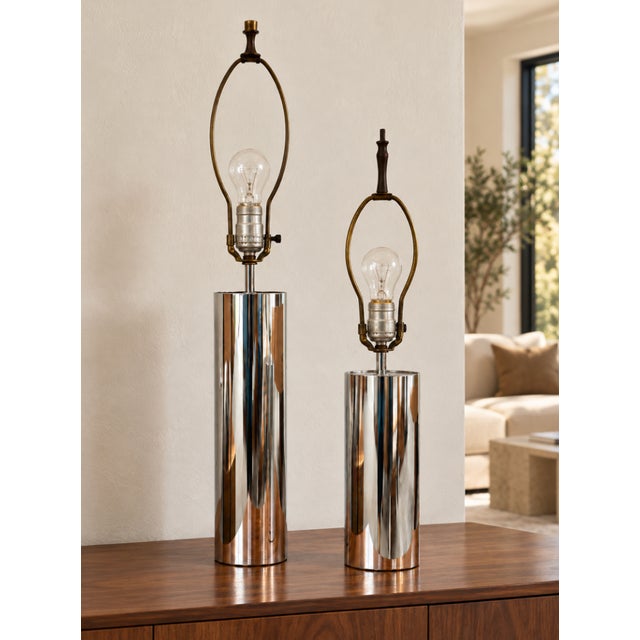 Set of two Mid Century Modern Chrome table lamps featuring sleek cylindrical bases and a reflective finish. Their clean...