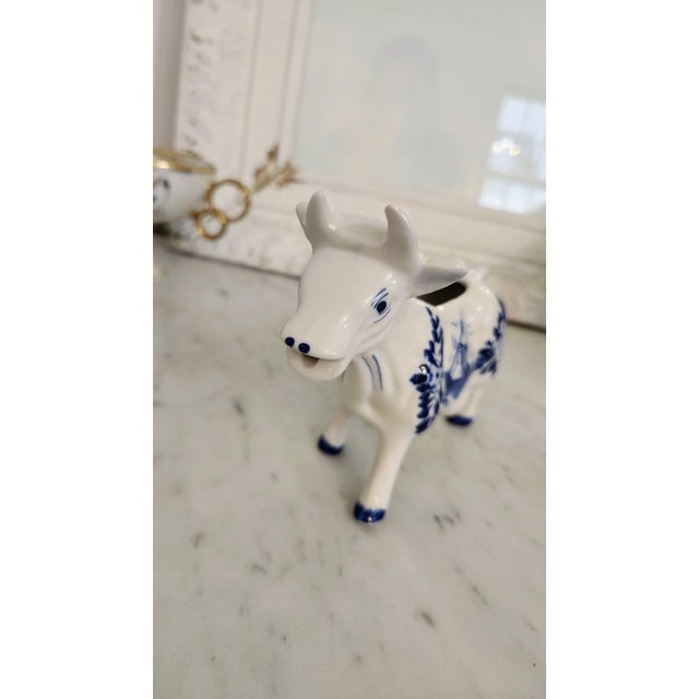 A charming vintage Dutch cow-form creamer, hand painted in the traditional Delft Blue palette of cobalt blue and white....