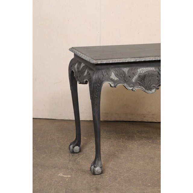 An English carved and painted wood console table with claw-and-ball feet. This vintage table from England has a...