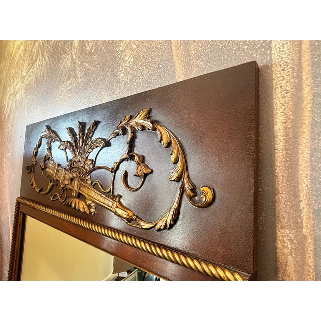 Elegant Empire-style wall mirror crafted in richly figured mahogany with a molded frame and an ornate brass ormolu crest...